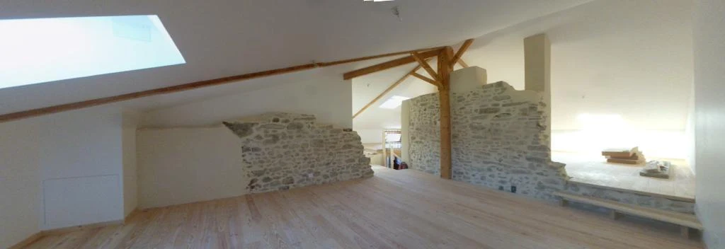 Combles rénovés avec mur en pierre apparent et charpente bois